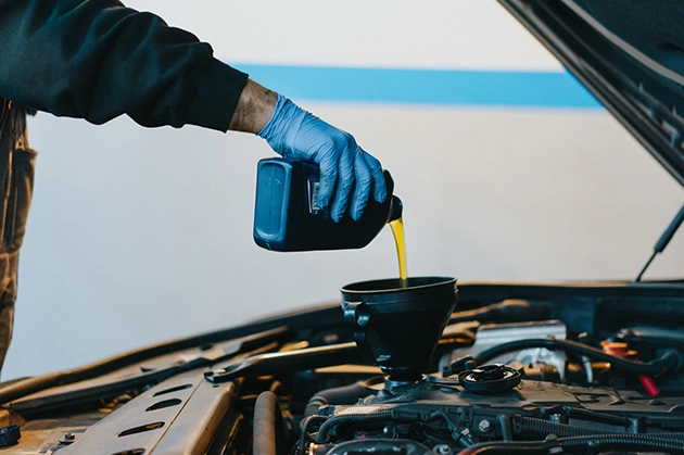 Mechanic Pouring Oil into Car Engine During Oil Change Service