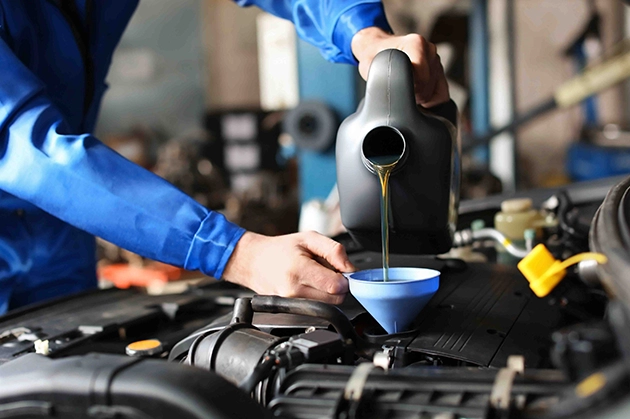 Mechanic Pouring Oil into Engine Using a Funnel